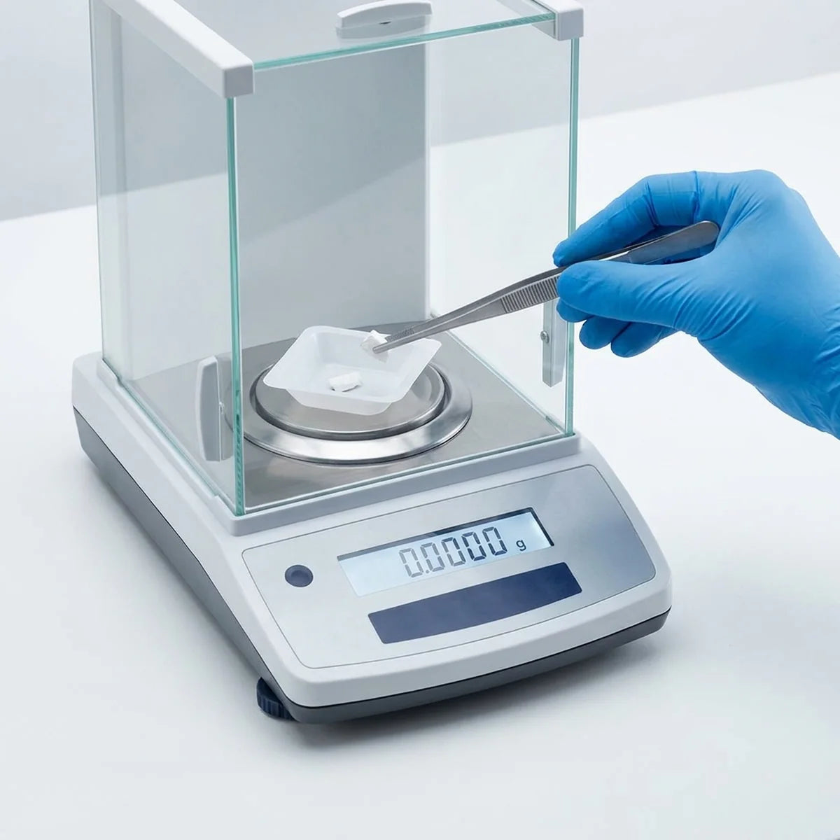 Forceps placing sample on analytical balance