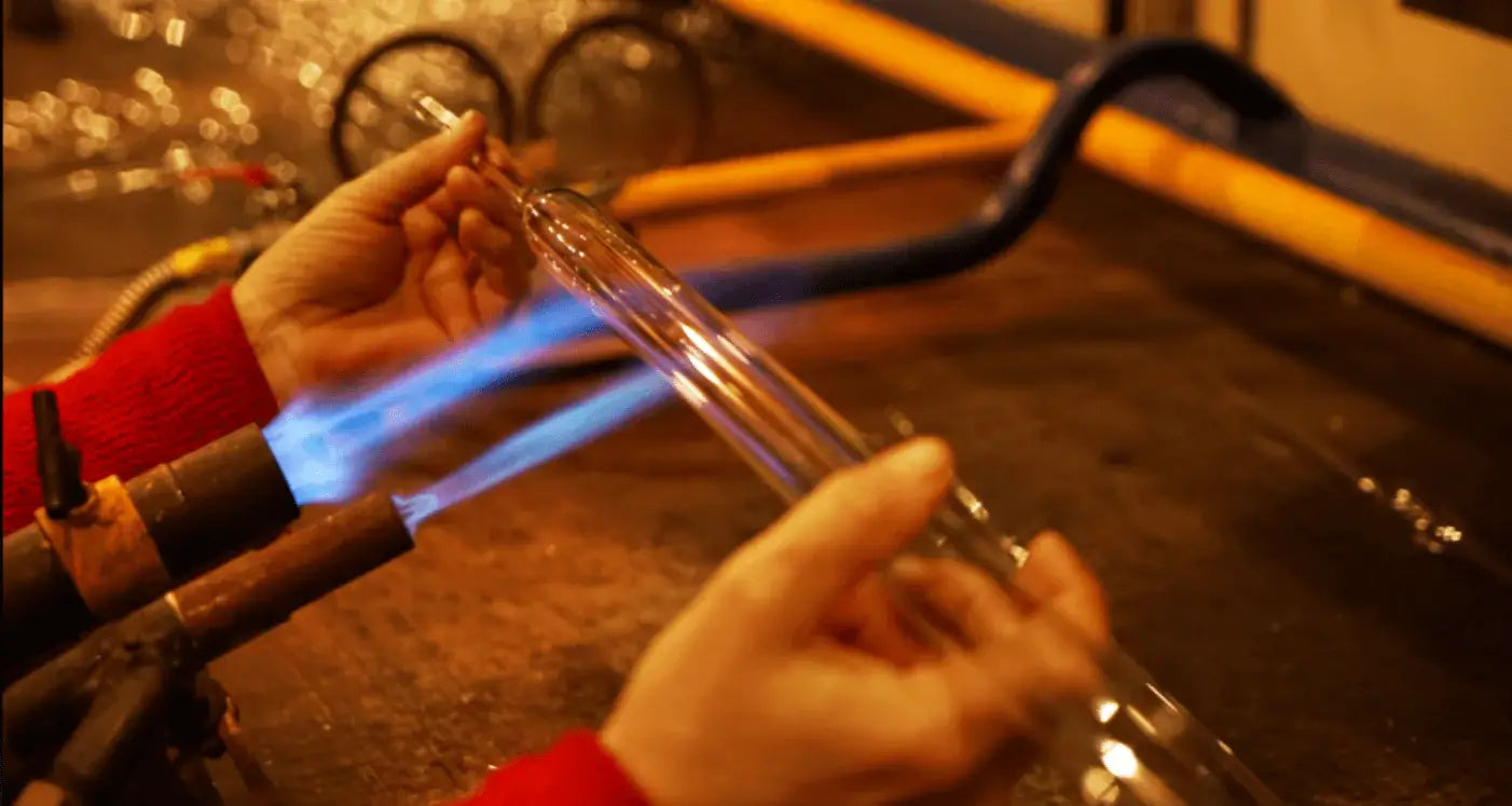 Glassblowing process with artisan forming a glass rod