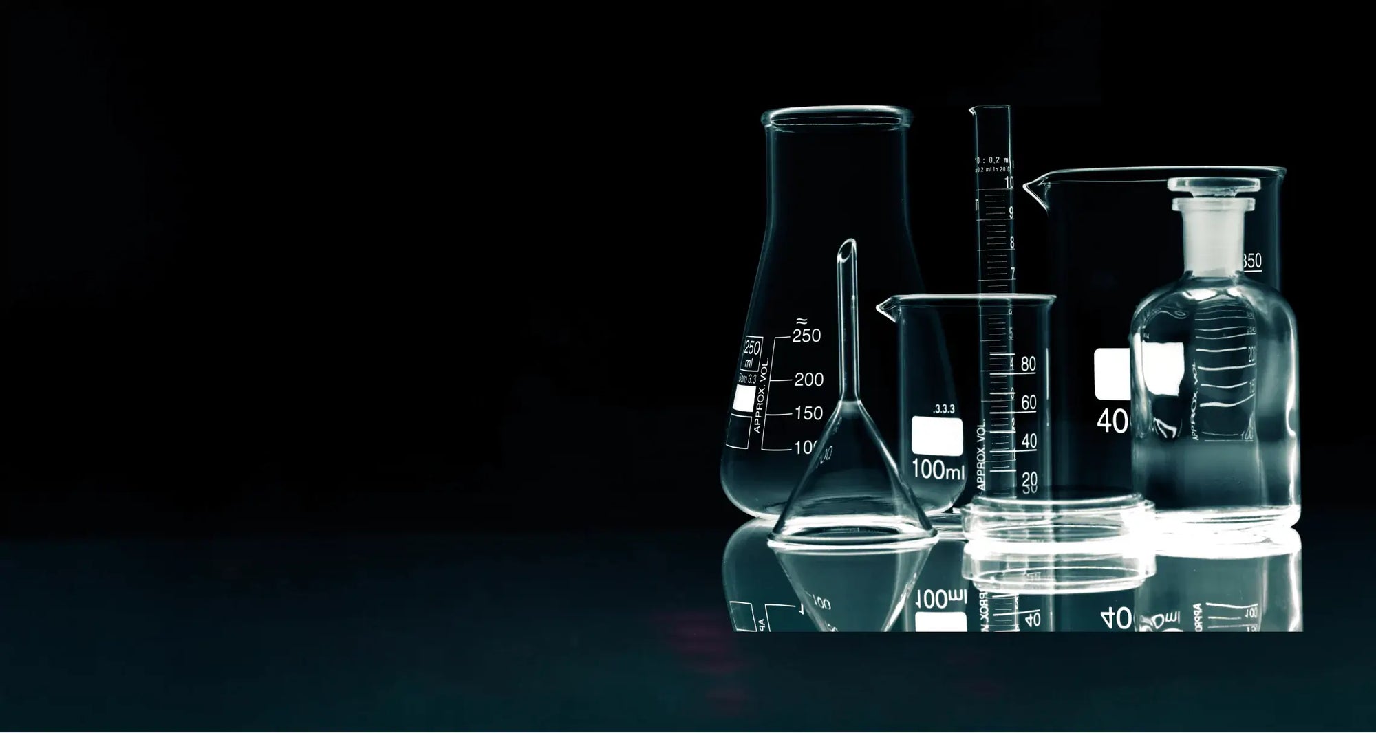 Set of laboratory beakers with measurements on a reflective surface