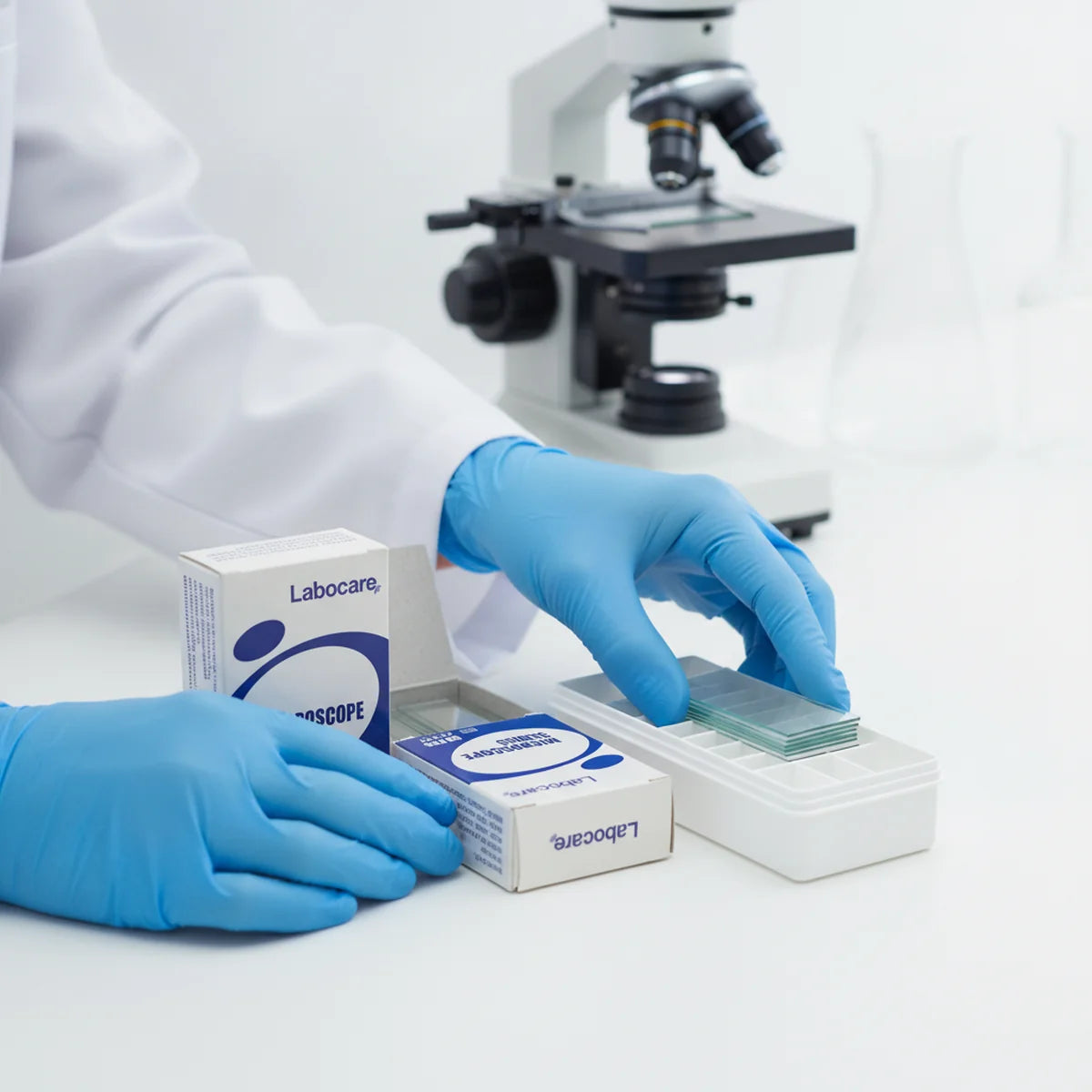 Researcher loading blank glass microscope slides into a storage box