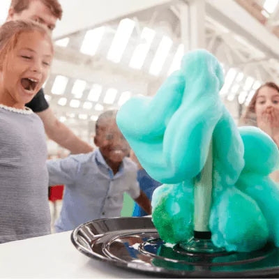 Children watching a science experiment with blue foam using laboratory equipment in a classroom