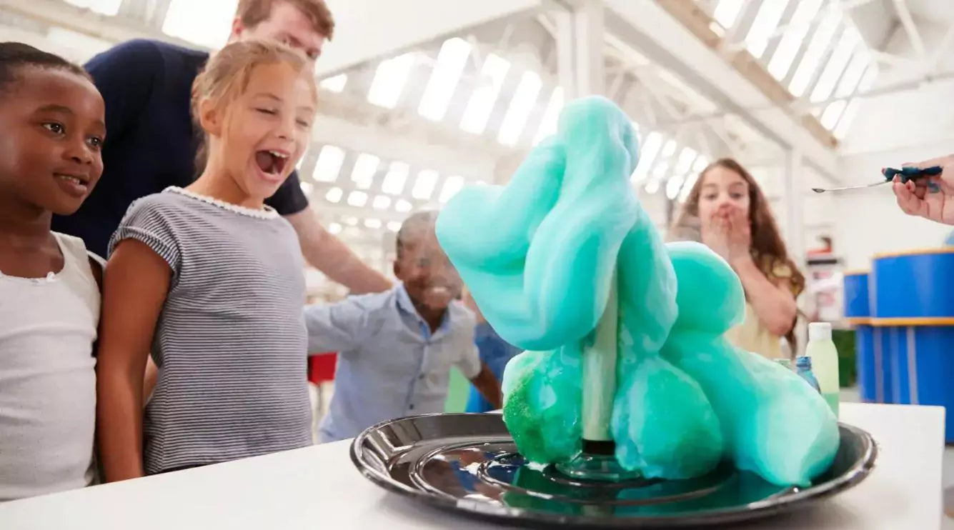 Children watching a science experiment with blue foam in a classroom setting