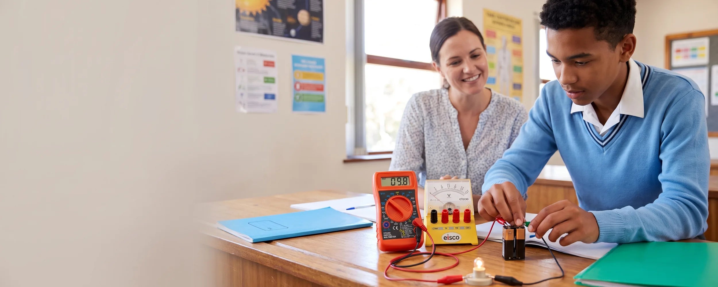Student and teacher using a voltmeter and multimeter in a classroom circuits practical
