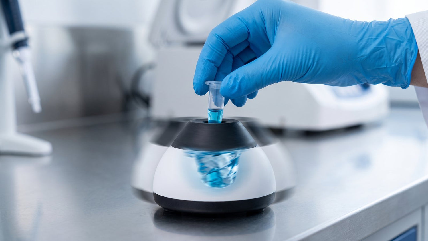 Microcentrifuge tube pressed against a vortex mixer with visible motion blur